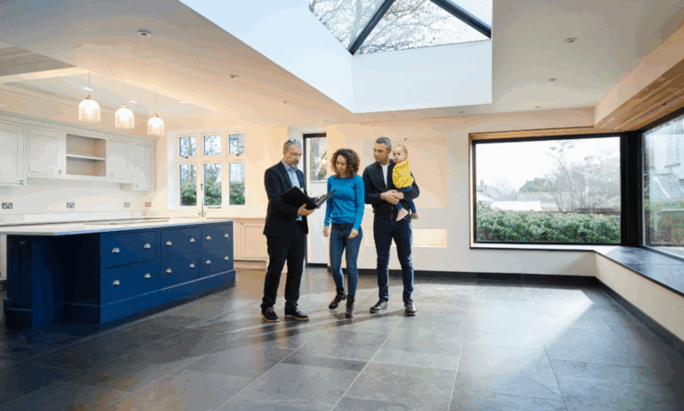 Spacious open-plan living room with large sofas, natural light and a modern white kitchen.