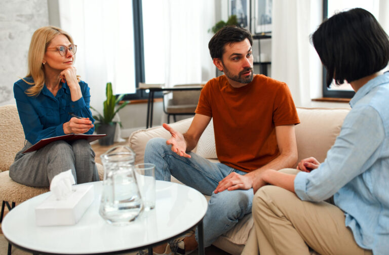 Landlord discussing tenancy terms with tenants and advisor, representing rent in advance compliance and legal review under new regulations